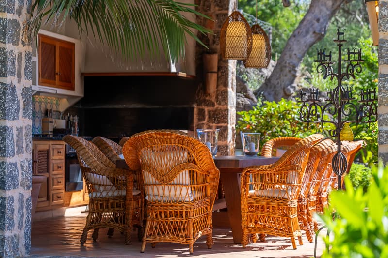 The wicker dining setting at Son Salas, lamps lit, table set for the evening